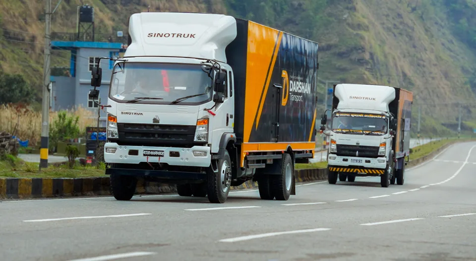 Two Darshan Transport trucks in convoy on a mountain highway