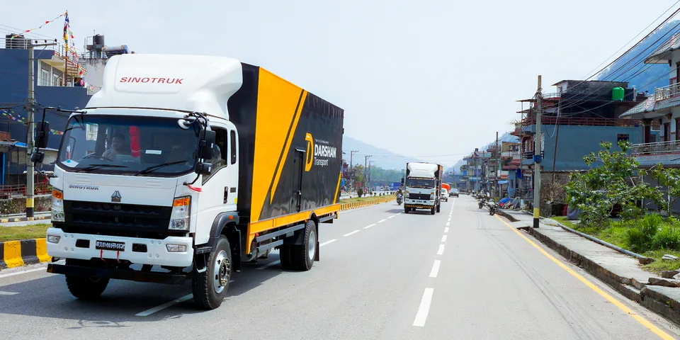 Darshan Transport branded truck approaching, front three-quarter view