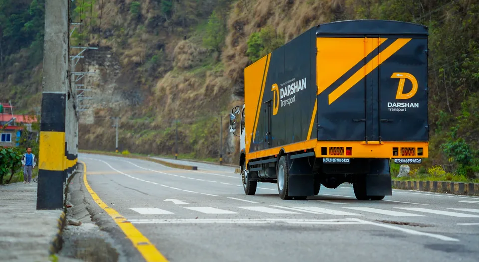 Darshan Transport truck driving a forested mountain highway